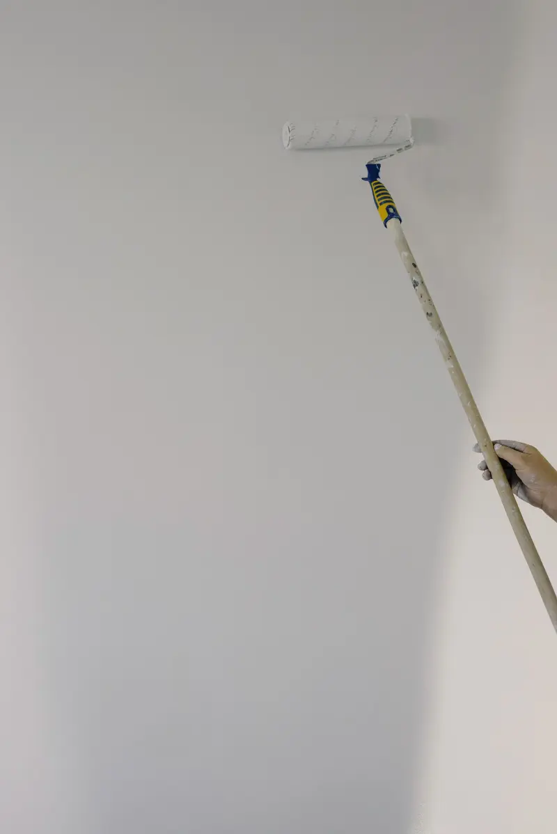 Painter using an extension pole roller on a wall
