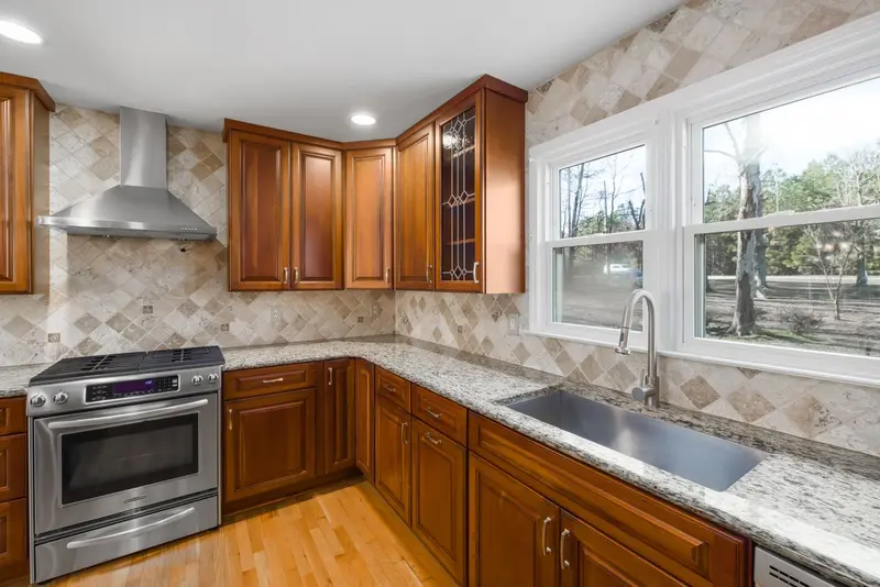 Kitchen with wood cabinets, granite counters, and a window over the sink